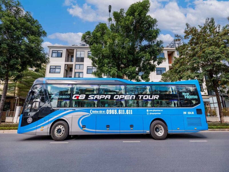 a blue and white bus on the street - g8-sapa-open-tour