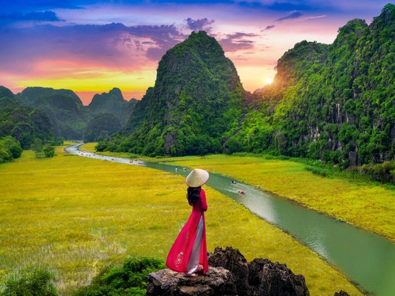 a woman standing on a rock overlooking a river and mountains - Ninh Binh full day tour from Ha Noi