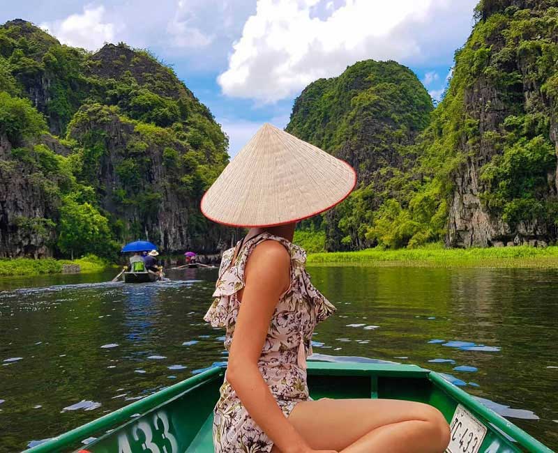 a woman in a boat on water with mountains in the background